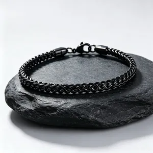 Macro view of a 3mm black stainless steel dragon-bone chain bracelet displayed on a dark stone.