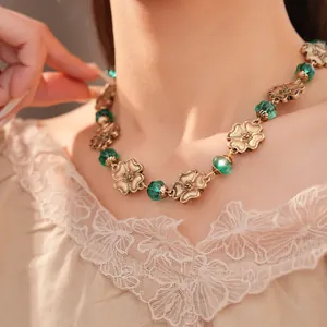 Detailansicht einer goldenen Vintage-Blumenkette mit grünen Harzperlen an einem Modell getragen