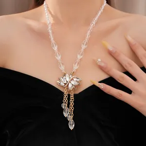 Detail van kristallen kralenketting met bloemhanger en druppelvormige kwastjes