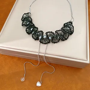 Detail van de handgemaakte kralen kant ketting met grijze parels en hartjes hangers