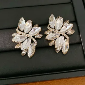 Detailopname van elegante kristallen blad oorbellen met goudkleurige pave accenten