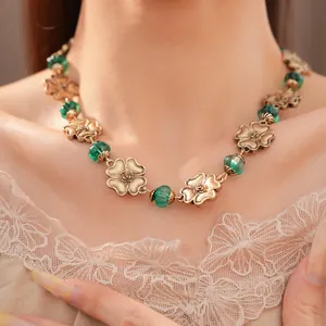 Vintage goldene Blumenkette mit grünen Harzperlen, getragen für einen Retro-Look.