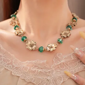 Detailansicht einer Vintage-Goldblumenkette mit smaragdgrünen Harzperlen am Modell