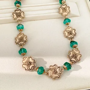 Detailansicht einer Vintage-Blumenkette mit grünen Harzperlen und goldenen Rosen.