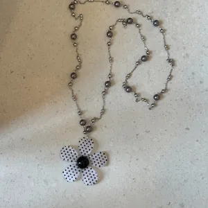 Gedetailleerde macrofoto van een parelketting met een acryl bloemhanger met zwarte stippen