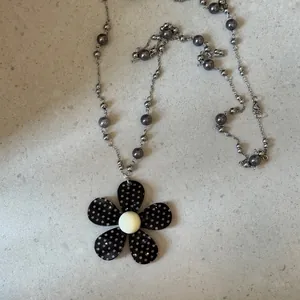 Detail van acryl bloemenhanger met stippen en grijze kralen aan een zilveren ketting