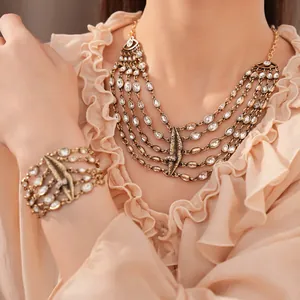 Detail eines vintage goldfarbenen Halsketten-Sets mit Kristallen und Lippen-Charm