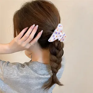 Macro view of white acrylic floral hair claw clip used on a braided hairstyle