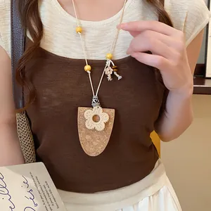 Detail van de boheemse kurkbloem hanger ketting gedragen door een model in een outfit