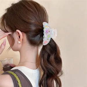 Detailed view of a sweet acrylic hair claw clip with colorful butterfly prints on a bun