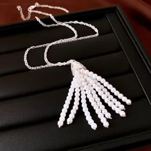 Detailaufnahme des eleganten silbernen Quastenanhängers mit weißen Perlensträngen