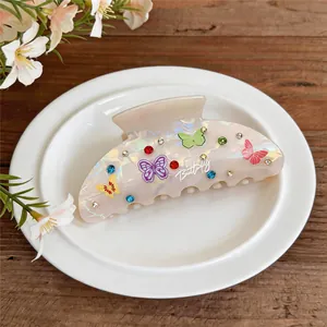 Detail of acrylic hair claw clip with colorful butterfly prints and rhinestones