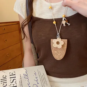 Detailweergave van een ketting in Boheemse stijl met bloem- en kurkhangerbedeltje.