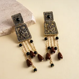 Gros plan détaillé de boucles d'oreilles vintage dorées avec métal ciselé et pampilles