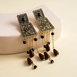 Vue détaillée de boucles d'oreilles vintage en métal avec glands en acrylique rouge foncé