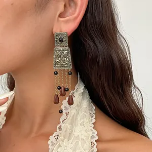 Gros plan de boucles d'oreilles vintage en métal avec perles acryliques brunes portées par un modèle