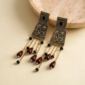 Gros plan détaillé de boucles d'oreilles vintage dorées avec pompons en acrylique brun