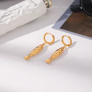 Vue détaillée de boucles d'oreilles créoles avec pendentif poisson doré pour un look chic.