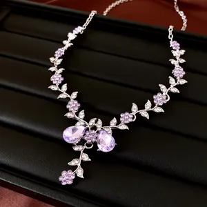 Elegante Halskette mit lila Kristallen, Blumen und Blättern auf Schmucktablett.