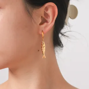 Détail des boucles d'oreilles pendantes en forme de poisson doré sur un mannequin