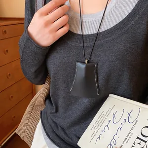 Detail van zwart geometrisch leren sleuteltasje aan ketting als hanger