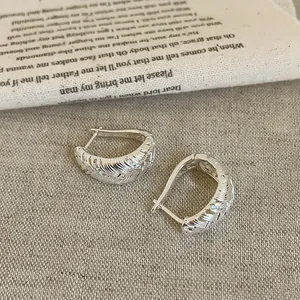 Nahaufnahme der geflochtenen Textur und Zirkonia-Details an 18 Karat vergoldeten Creolen