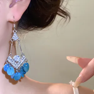 Detailopname van vintage strass oorbellen met blauwe schelpkwastjes.