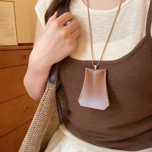 Detailopname van een bruine lederen clochette ketting met witte contraststiksels