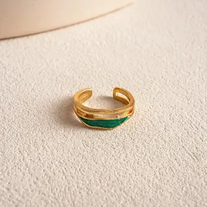 Detailaufnahme eines antiken, unregelmäßigen goldfarbenen Rings mit grüner Emaille