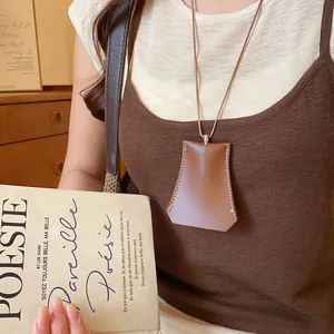 Detailweergave van een bruine geometrische lederen sleuteletui ketting gedragen als hanger.