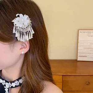 Detailed view of an elegant Chinese-style pearl flower hair clip with tassels on a model