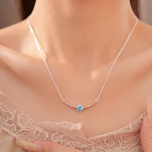 Minimalist silver clavicle chain featuring a curved bar with a central light blue zircon.