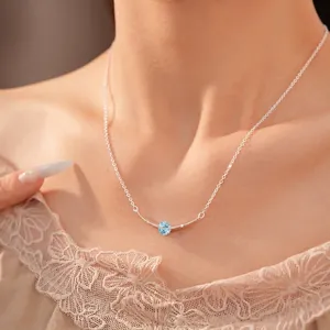 Minimalist silver necklace with a curved bar and blue zircon pendant on model