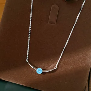 Macro-opname van een minimalistische gebogen zilveren ketting met blauwe zirkoon