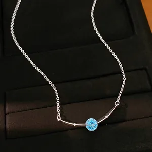 Detail van een zilveren ketting met een ronde blauwe zirkoon en gebogen hanger luxe