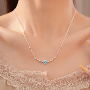 Elegante close-up van een zilveren gebogen staafketting met een heldere lichtblauwe zirkoon