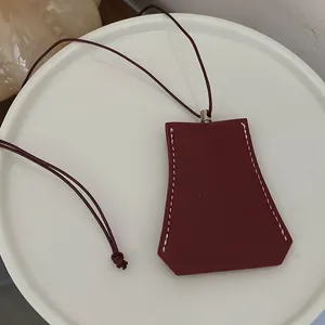 Nahaufnahme einer dunkelroten geometrischen Schlüsseltasche aus Leder mit weißen Nähten