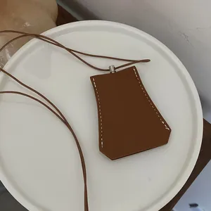 Detailansicht einer braunen geometrischen Schlüsseltasche aus Leder mit weißen Nähten