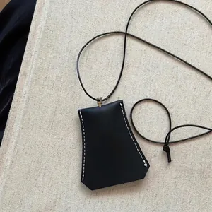 Detailaufnahme einer schwarzen Leder-Nackentasche mit weißen Nähten und Kordelzug.