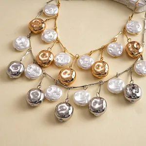A detailed macro view showcasing a vintage metallic textured and white pearl bead tassel necklace.