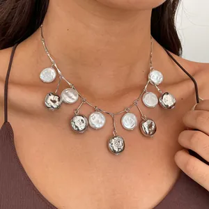 Close-up detail of retro metal wrinkled beads and white pearl fringe necklace on model's neck