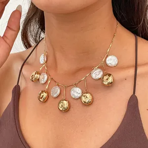 Detailed view of a vintage necklace with wrinkled gold beads and pearls on a model