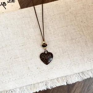 Gros plan du collier avec pendentif cœur léopard, cordon en cuir rustique et perles
