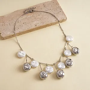 Close-up detail of retro metallic wrinkled beads and white baroque pearl fringe necklace