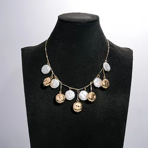Close-up of a vintage gold pleated metal necklace with white pearls on a black mannequin.