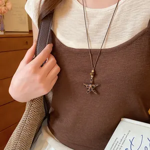 Détail du collier pendentif étoile léopard sur cordon marron porté par mannequin