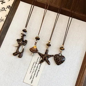 Gros plan de colliers à pendentifs léopard en forme d'ours et de cœur sur un plateau en bois.