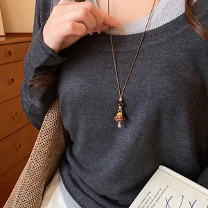 Détail d'un collier pendentif champignon vintage avec perle léopard sur cordon cuir