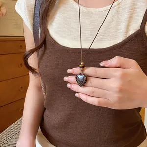 Gros plan d'un collier avec pendentif cœur léopard et cordon marron tressé