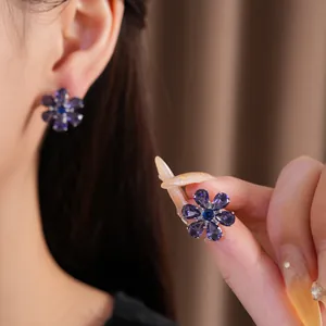 Gedetailleerde macro-opname van een elegante paarse zirkoon bloemoorbel in de hand